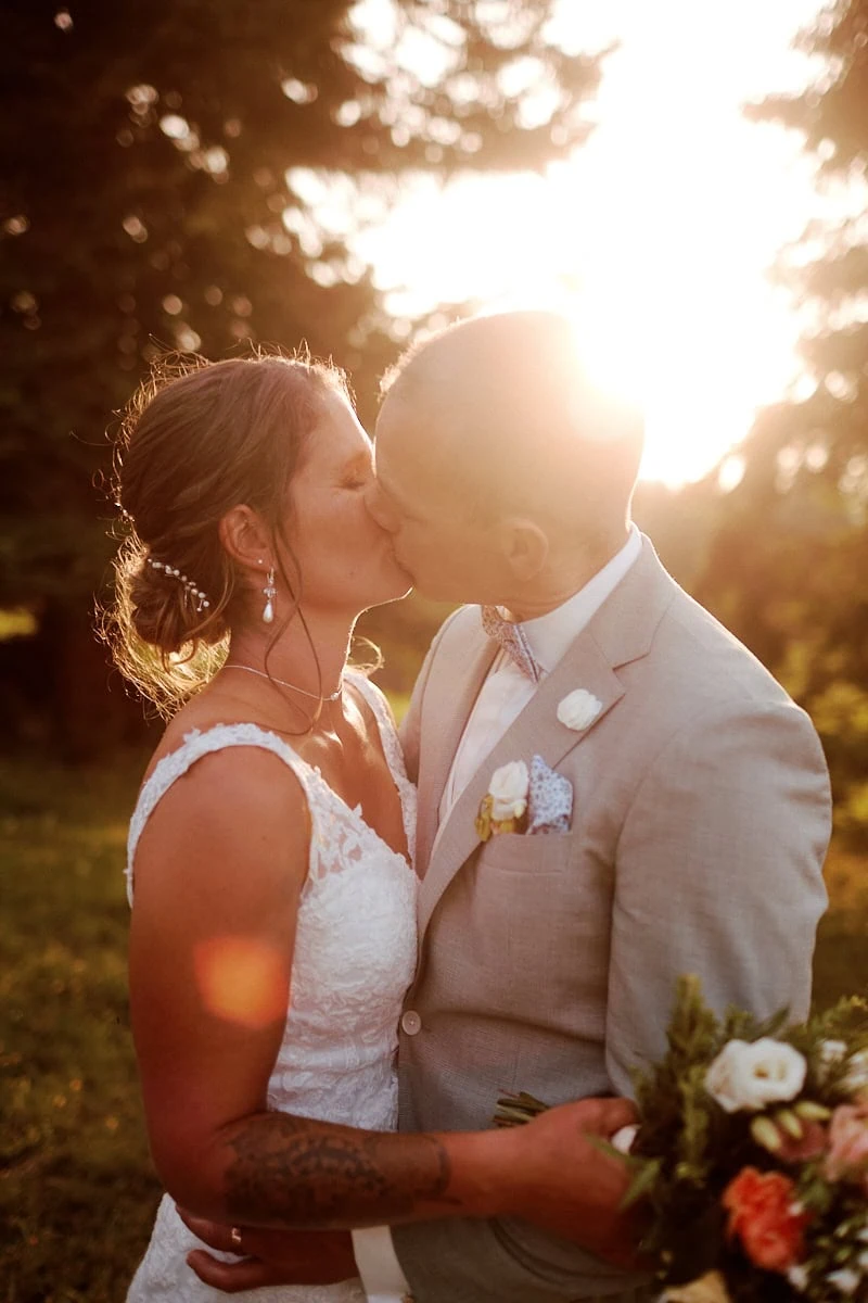 Couple de mariés s'embrassant au coucher du soleil