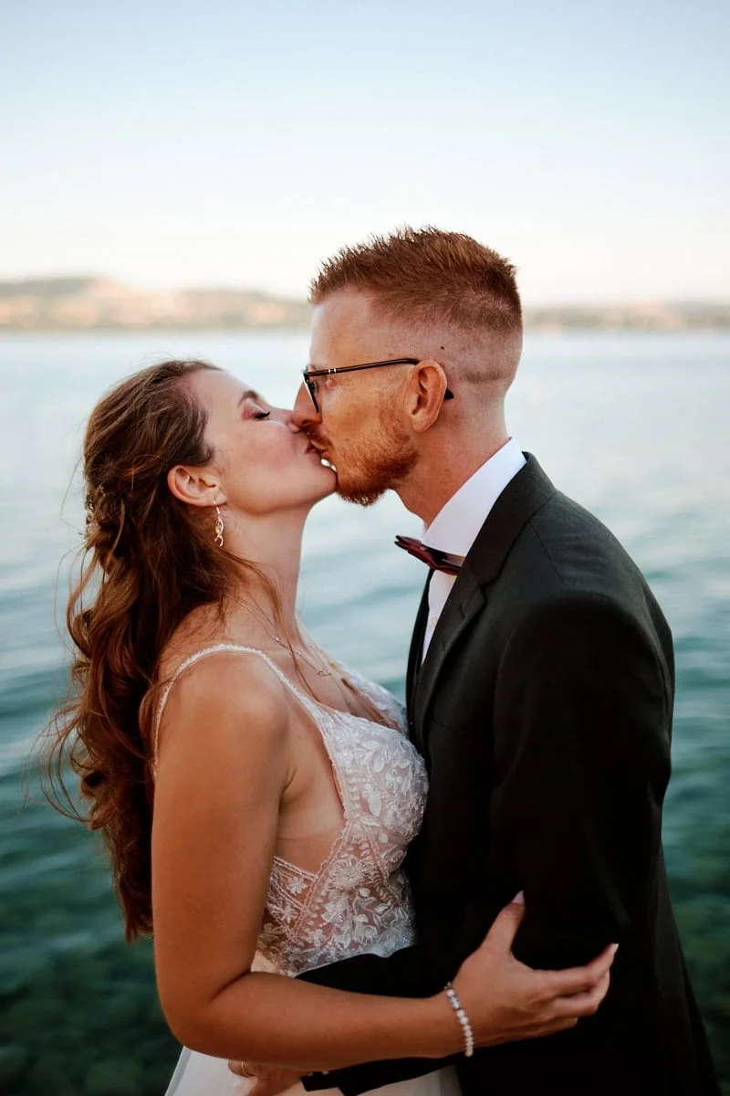 Mariés s’embrassant devant un lac paisible
