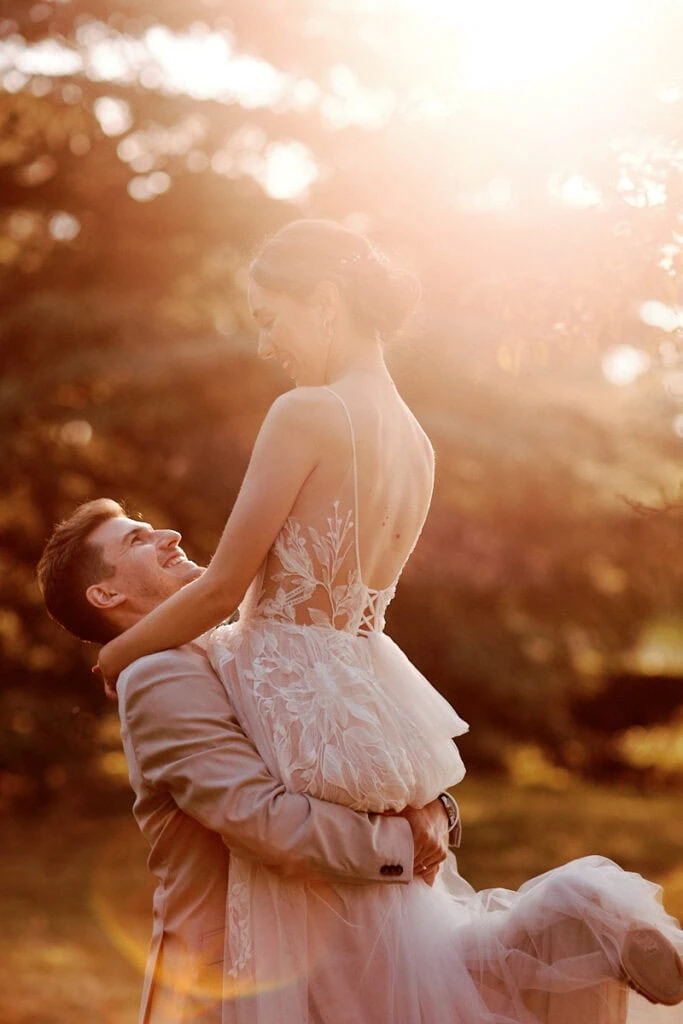 Le marié porte la mariée dans la lumière du soir