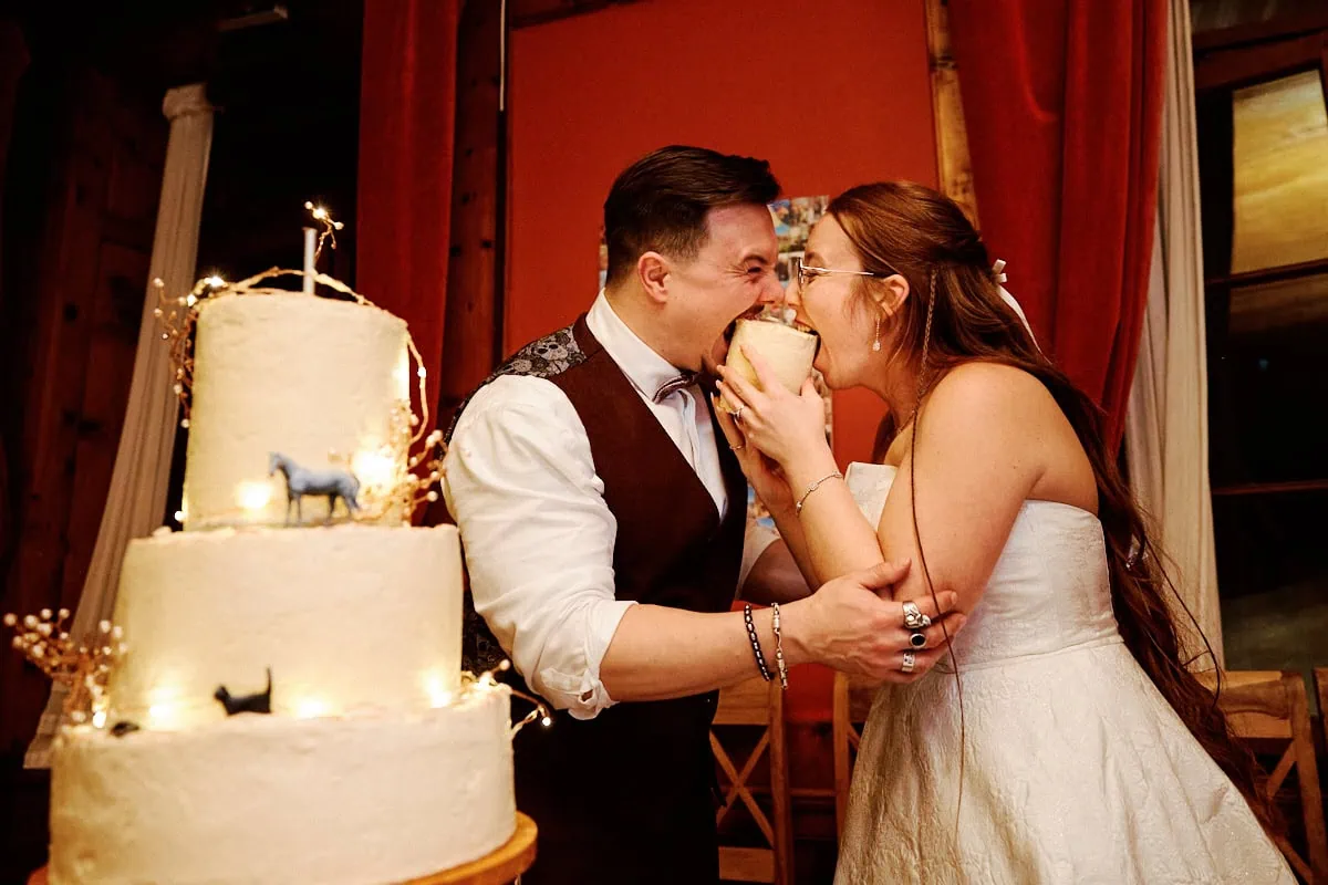 Mariés rient en partageant une part de gâteau.