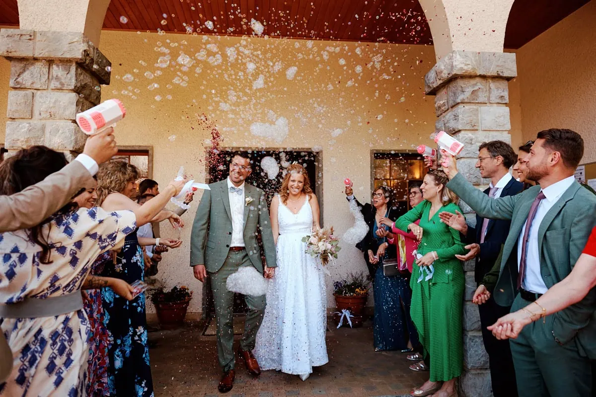 Sortie joyeuse des mariés sous bulles et confettis