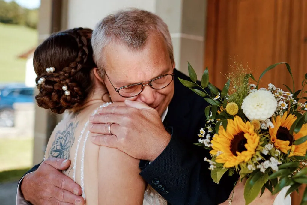 Câlin père-fille à l’arrivée de la mariée, émotion familiale impossible à refaire.
