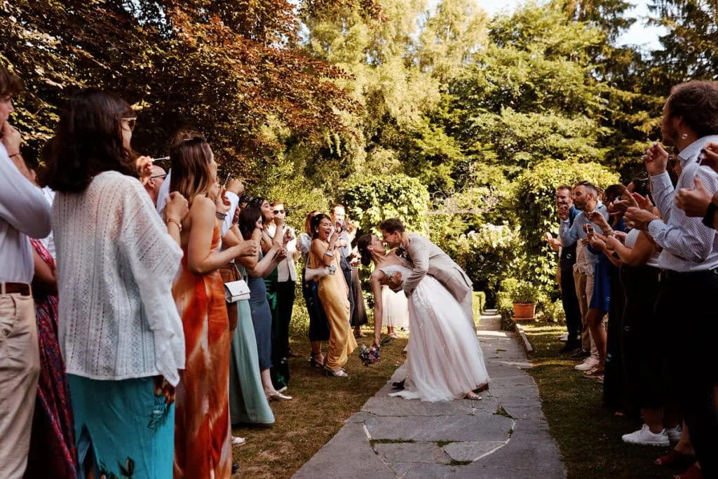 Pourquoi prendre un photographe de mariage : sortie de cérémonie et baiser des mariés, moment clé capté au bon instant.