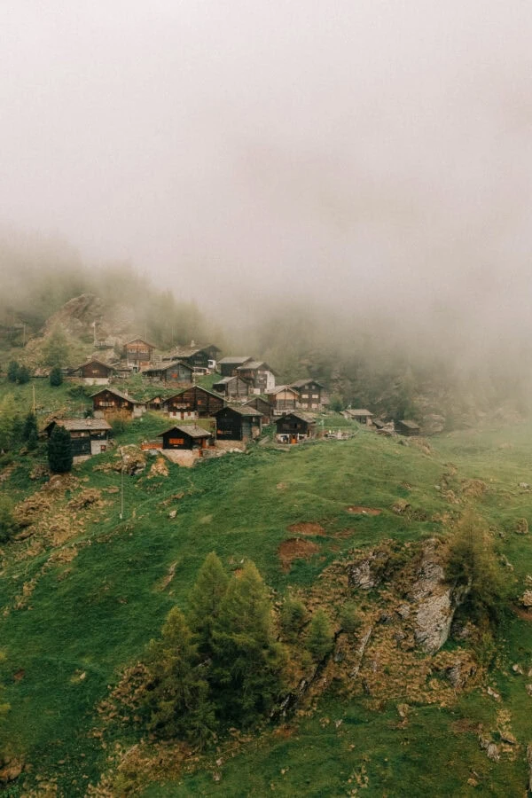 Village alpin brumeux sur colline verdoyante