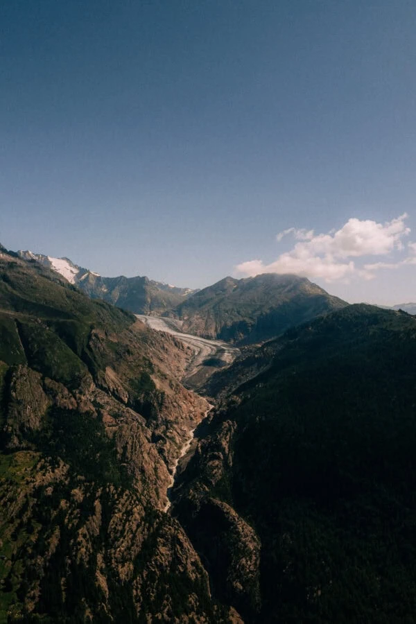 Glacier serpentant entre montagnes rocheuses sous ciel bleu
