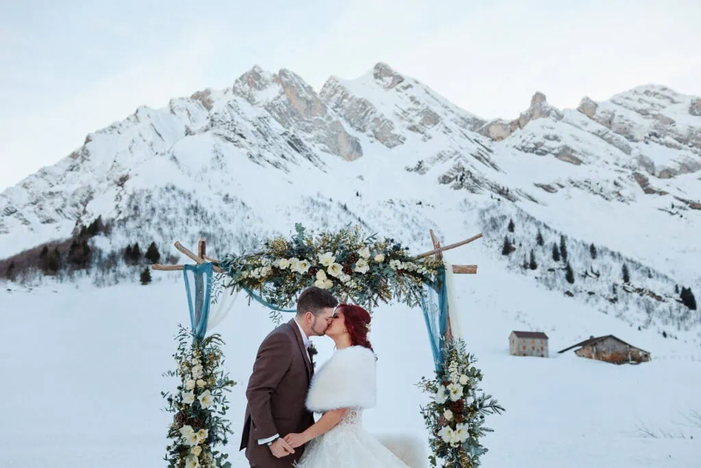 Mariés s’embrassant devant montagnes enneigées lors d'une cérémonie laïque