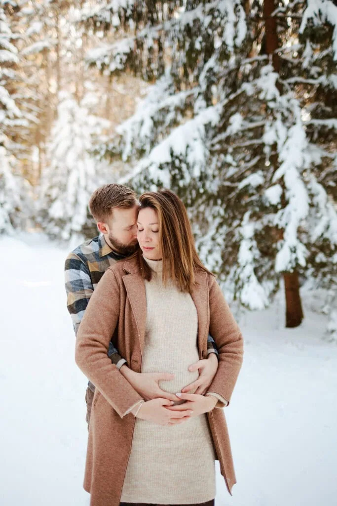 Couple attendant un bébé dans forêt enneigée