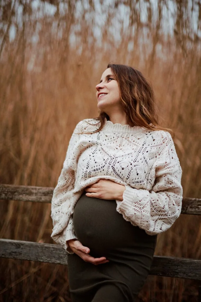 Femme enceinte souriante près d’une clôture en bois