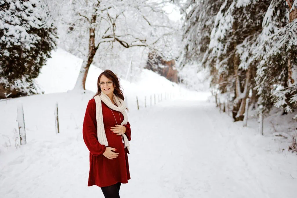 Femme enceinte en robe rouge dans la neige